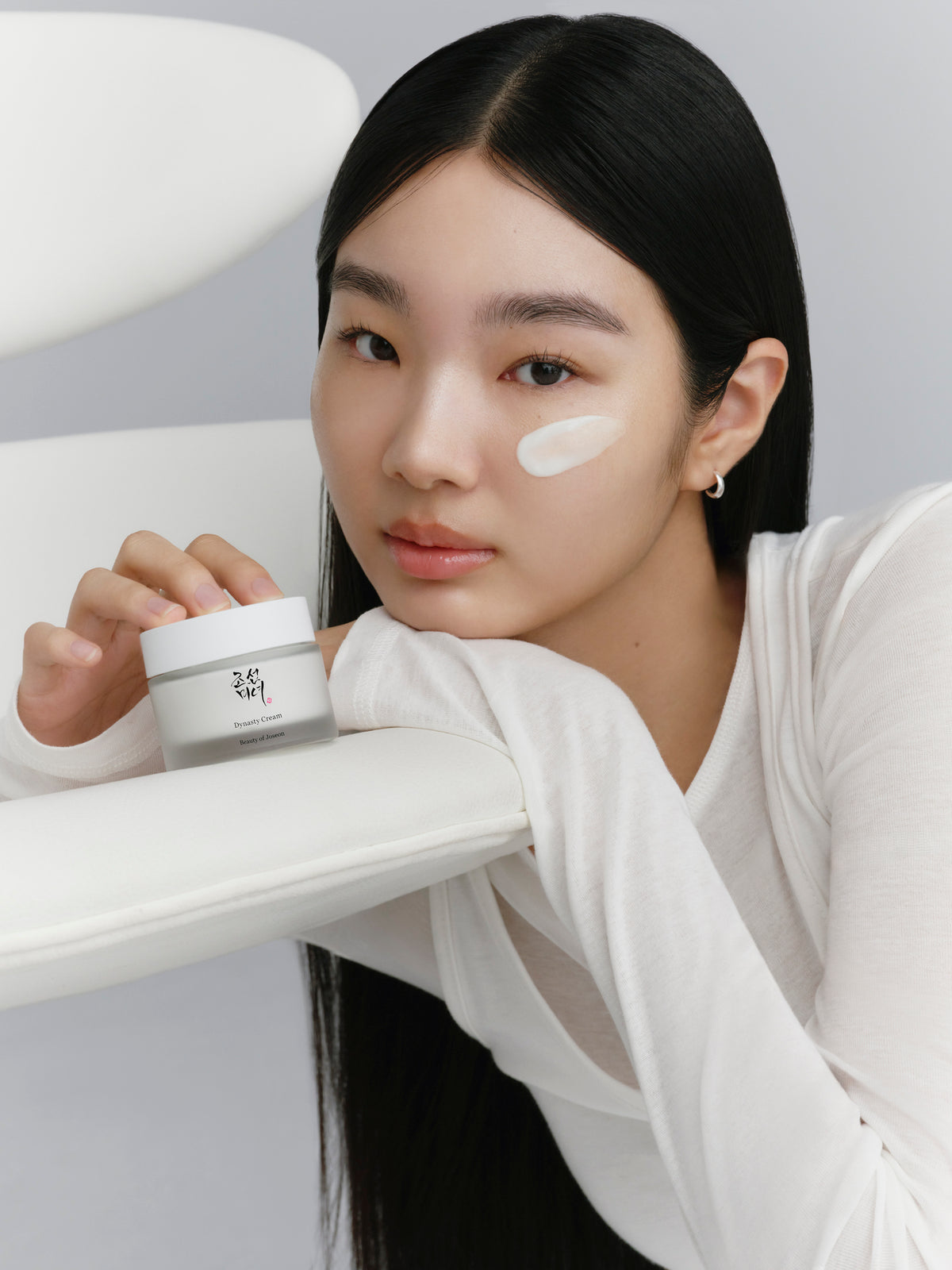 A model touching the Beauty of Joseon cream placed on a table.